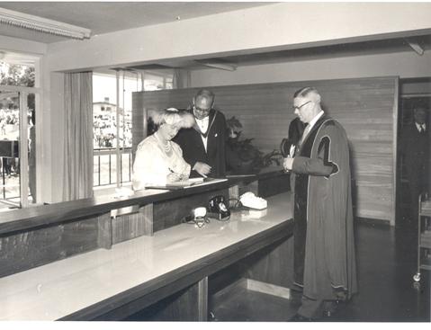 Her Majesty Queen Elizabeth, the Queen Mother assisted by the Principal Sir Bernard de Bunsen signs the visitors' book in the New Library Building at Makerere University, Kampala Uganda on 20th February 1959