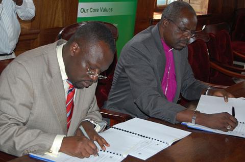 The Ag. Vice Chancellor Prof. V. Baryamureeba (L) and His Grace Henry Luke Orombi sign the MoU between CoU and Makerere University during the His Grace's visit, 24th August 2011, Makerere University, Kampala Uganda.