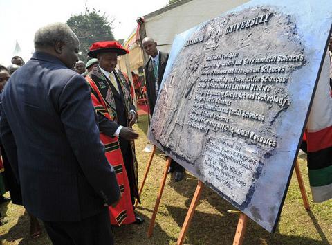 Presidents Mwai Kibaki of Kenya (L) and Yoweri Kaguta Museveni of Uganda (2nd L) exchange views on the artwork of the plaque symbolizing the Launch of Constituent Colleges on 24th January 2012, Makerere University, Kampala Uganda.