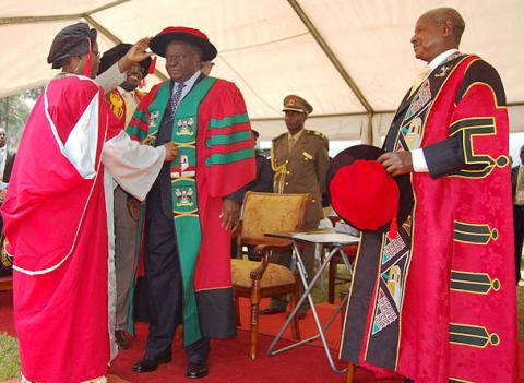 Kenyan President H.E. President Mwai Kibaki is adorned with the PhD gown and Cap by Prof. Grace K. Batebya and Ag. Vice Chancellor Prof. Venansius Baryamureeba during his Honorary Doctorate of  Laws Award ceremony, 24th January 2012, Makerere University, Kampala Uganda.