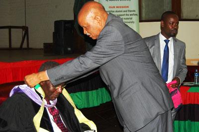 The Chancellor Prof. Mondo Kagonyera adorns Dr. Aliker.