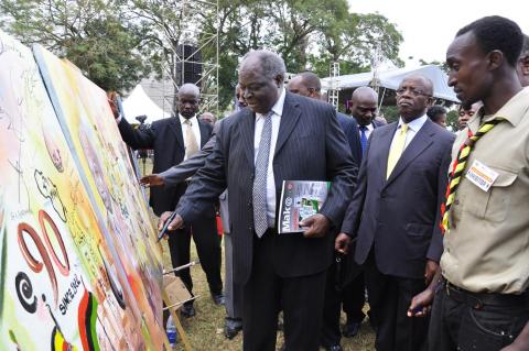 H.E. Dr. Mwai Kibaki signs the Mak@90 Grand Finale commemorative live painting accompanied by Prime Minister, Rt. Hon. Amama Mbabazi (2nd R), 3rd August 2013, Makerere University, Kampala Uganda. Right is the artist Rolands Tibirusya.